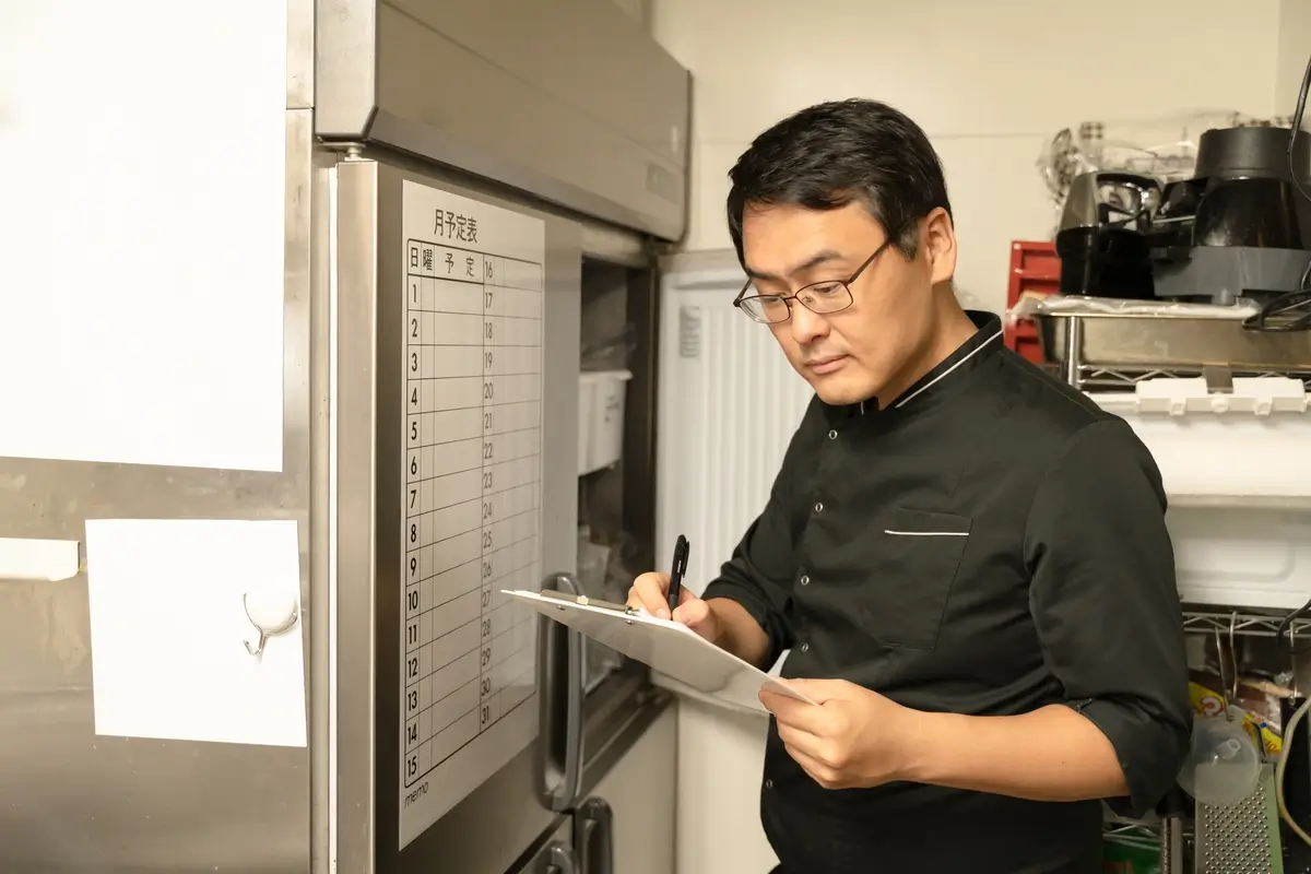Man checking a clipboard in a restaurant kitchen