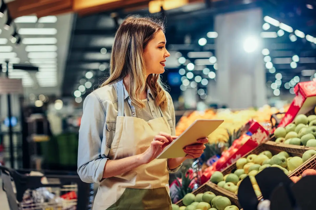 Woman holding a clipboard checking fresh fruit in a supermarket
